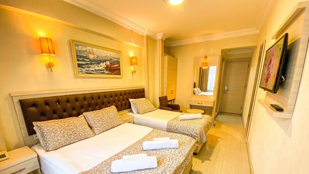 Une chambre d’hôtel avec deux lits, une grande fenêtre, un tableau et un téléviseur fixé au mur.