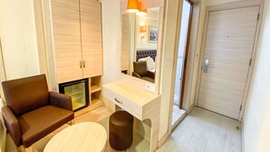 Une chambre moderne avec un canapé, une petite table ronde, un miroir et une armoire.