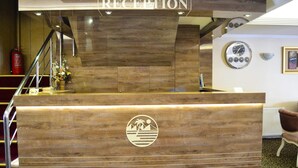 Un comptoir d’accueil avec un revêtement en bois, un logo et une horloge murale.