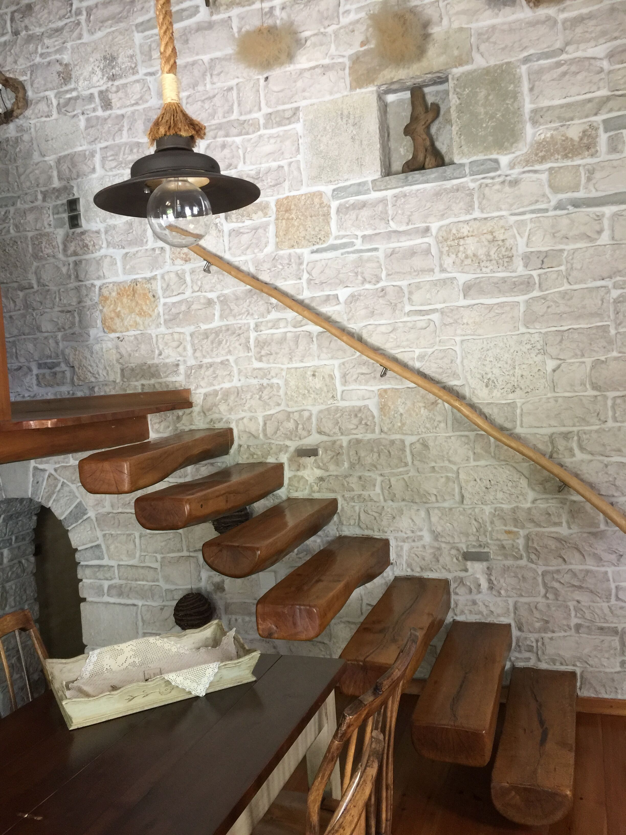 Una escalera rústica con escalones de madera y un colgador de luz.