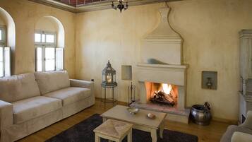Una sala de estar acogedora con chimenea, un sofá, una mesa de centro y un aparador con cristalería.