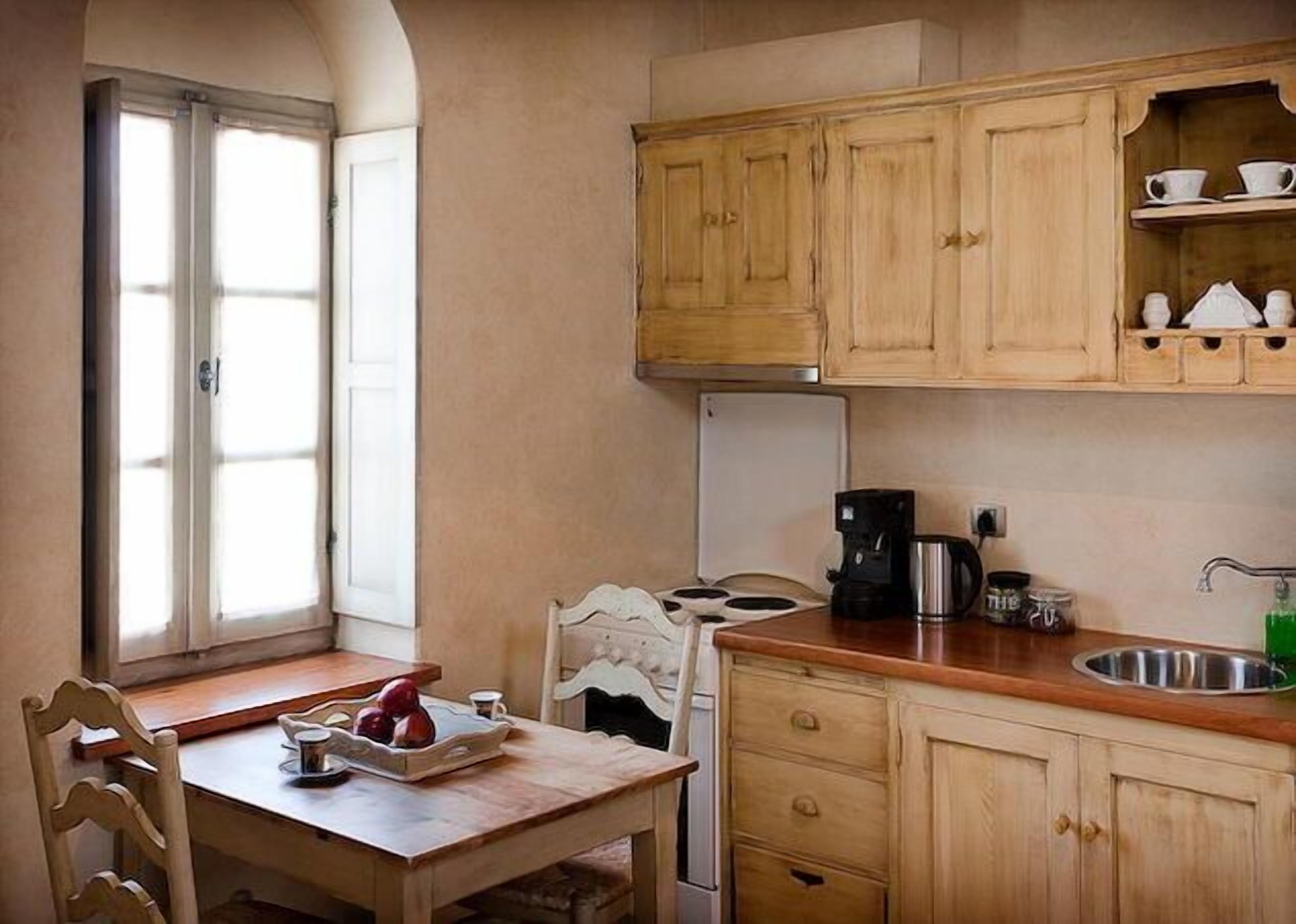 Una cocina compacta con armarios de madera, una cafetera y un lavamanos.