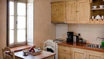 Una cocina compacta con armarios de madera, una cafetera y un lavamanos.