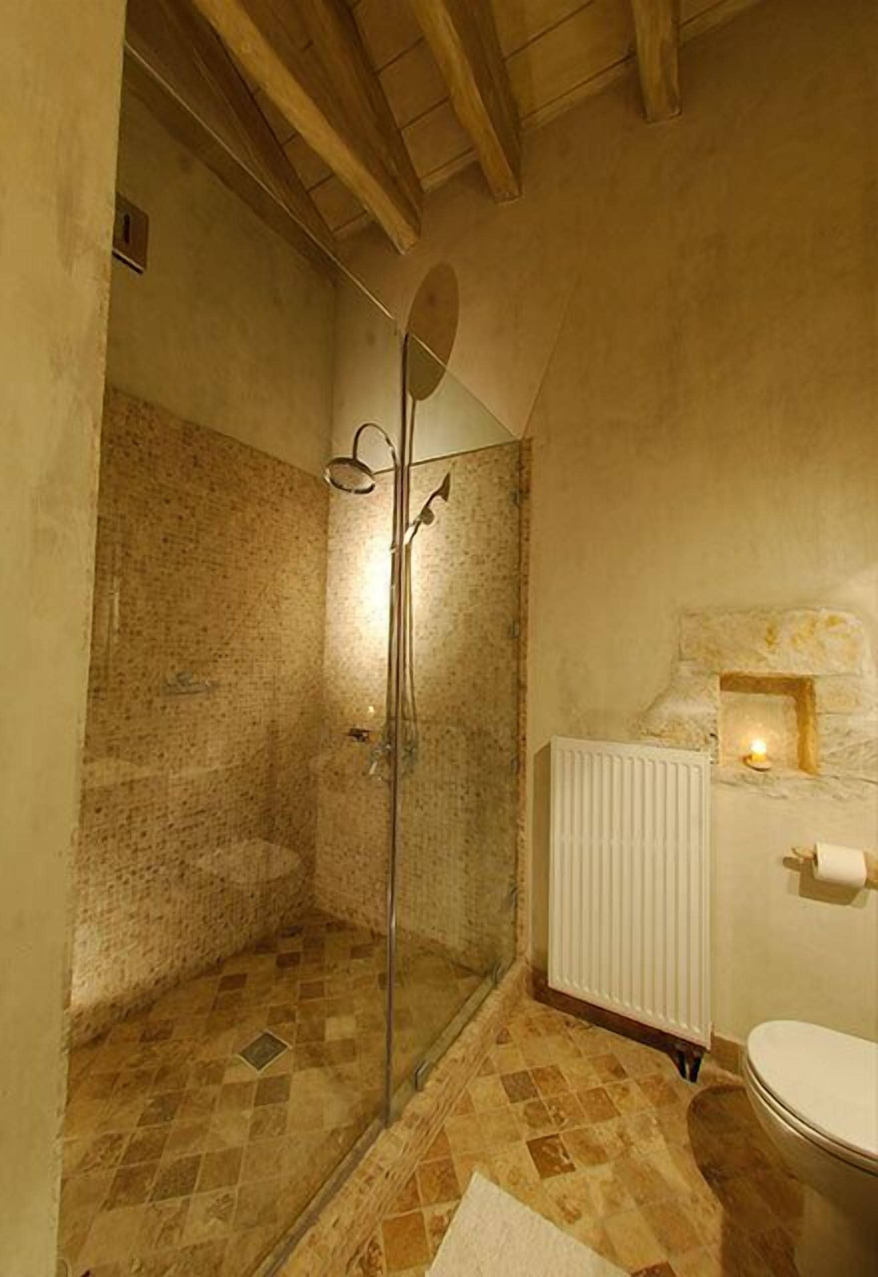 A bathroom with a shower, tiled floor, and a radiator.