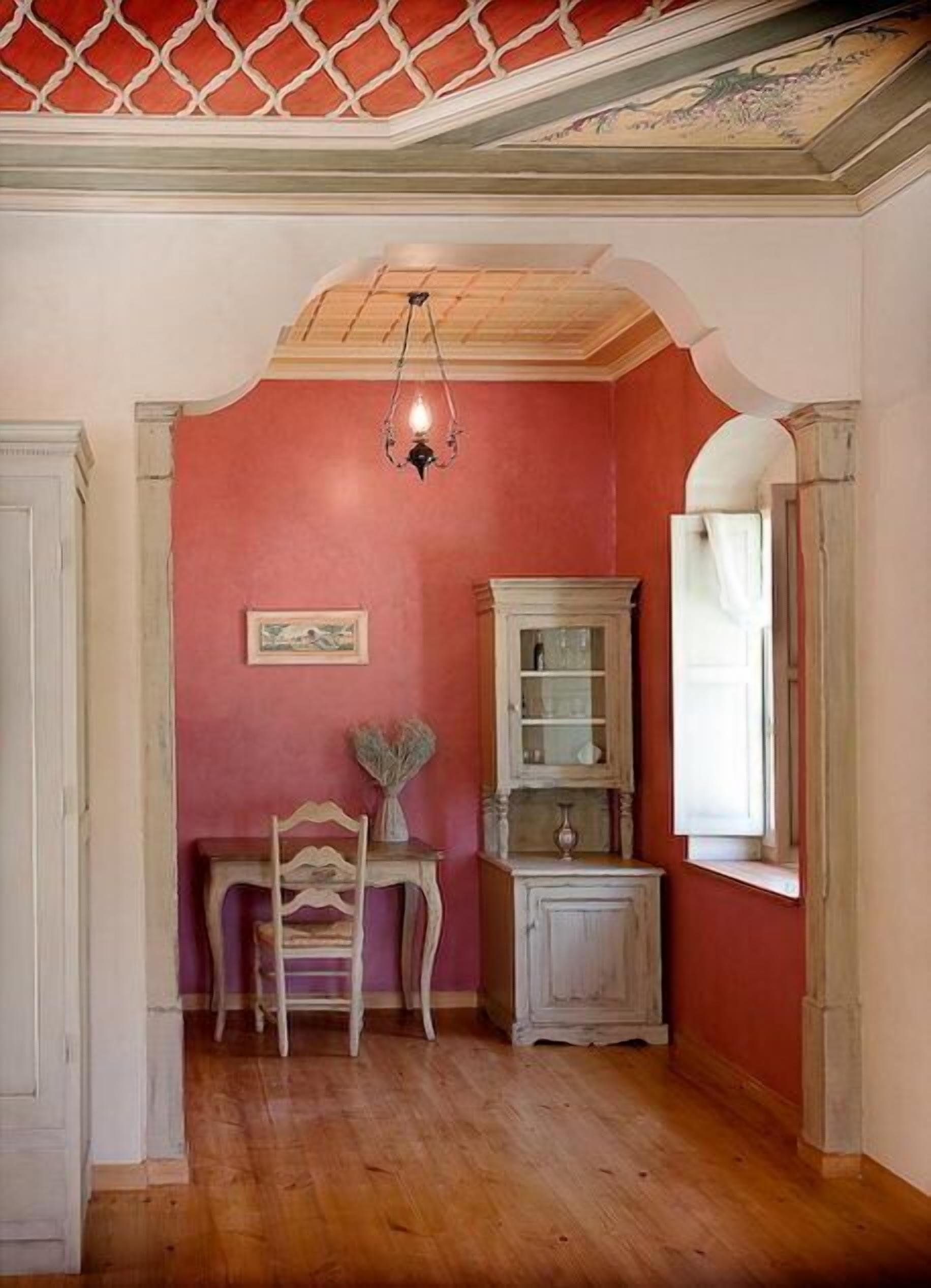 A room with a wooden floor, a chair, a cabinet, and a window with curtains.