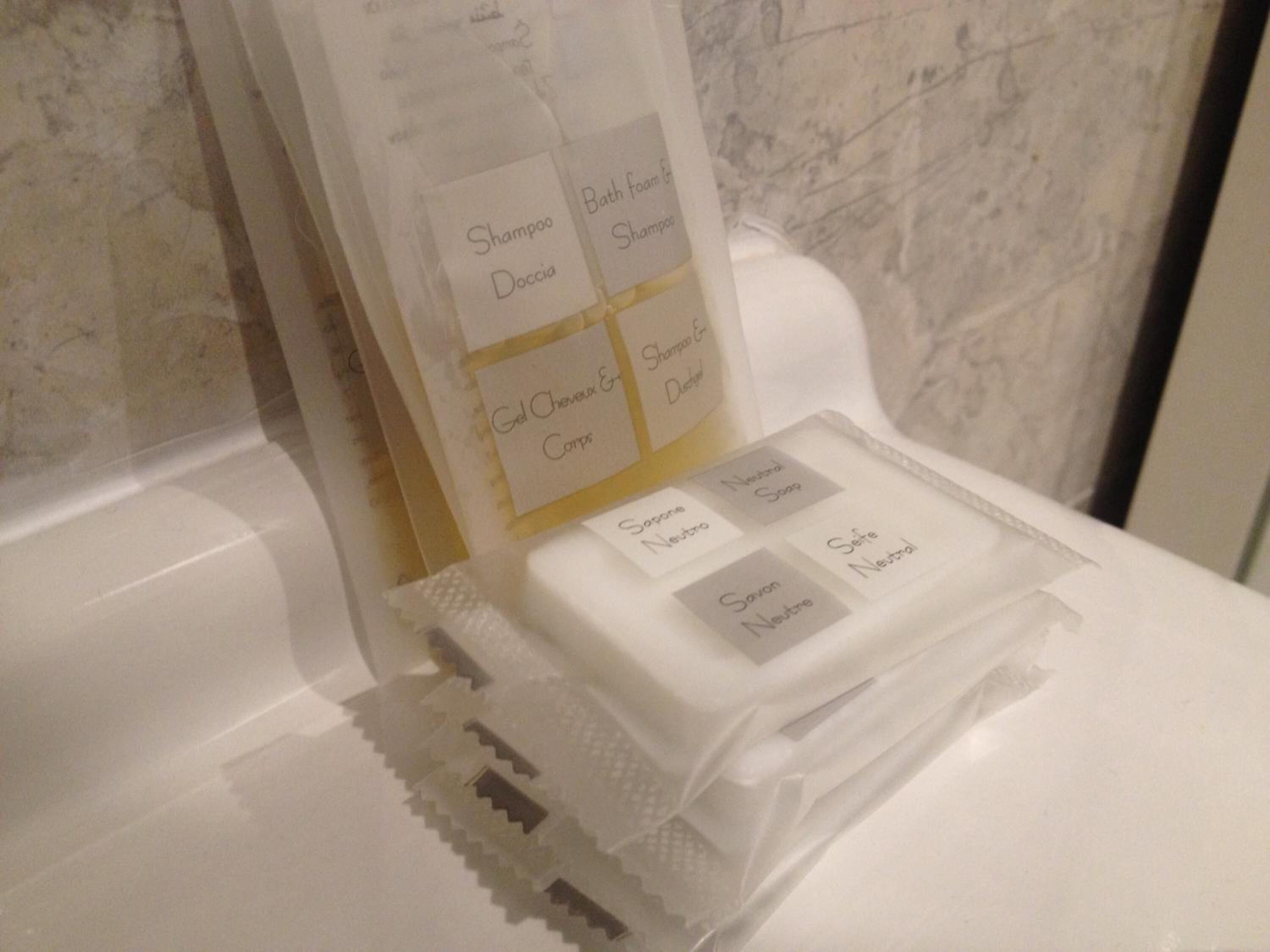 A bathroom with a white sink and a mirror. There are toiletries on the counter, including a bottle of shampoo and a bar of soap.
