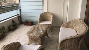 A balcony with wicker furniture, potted plants, and a water heater.