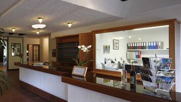 A reception area with a wooden counter, a glass display case, and a bookshelf.
