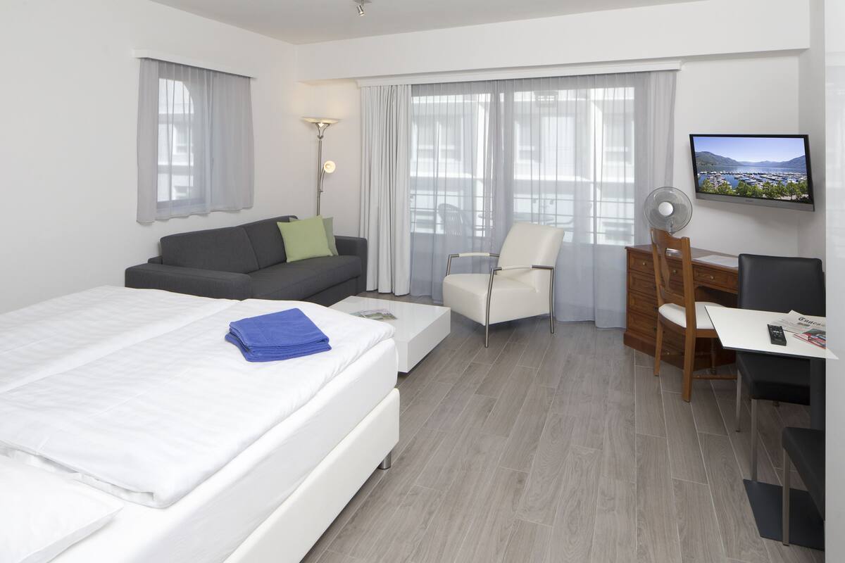 A hotel room with a bed, a sofa, a desk, and a chair.