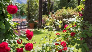 A garden with red roses and a seating area with tables and chairs. - Aparthotel al Lago (Locarno)