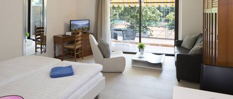 Une chambre d’hôtel moderne équipée d’un lit, d’un bureau, d’une chaise, d’un canapé et d’un balcon avec vue.