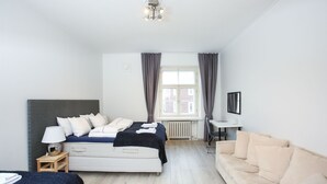 Et soveværelse med seng, sengebord, lampe og sofa.