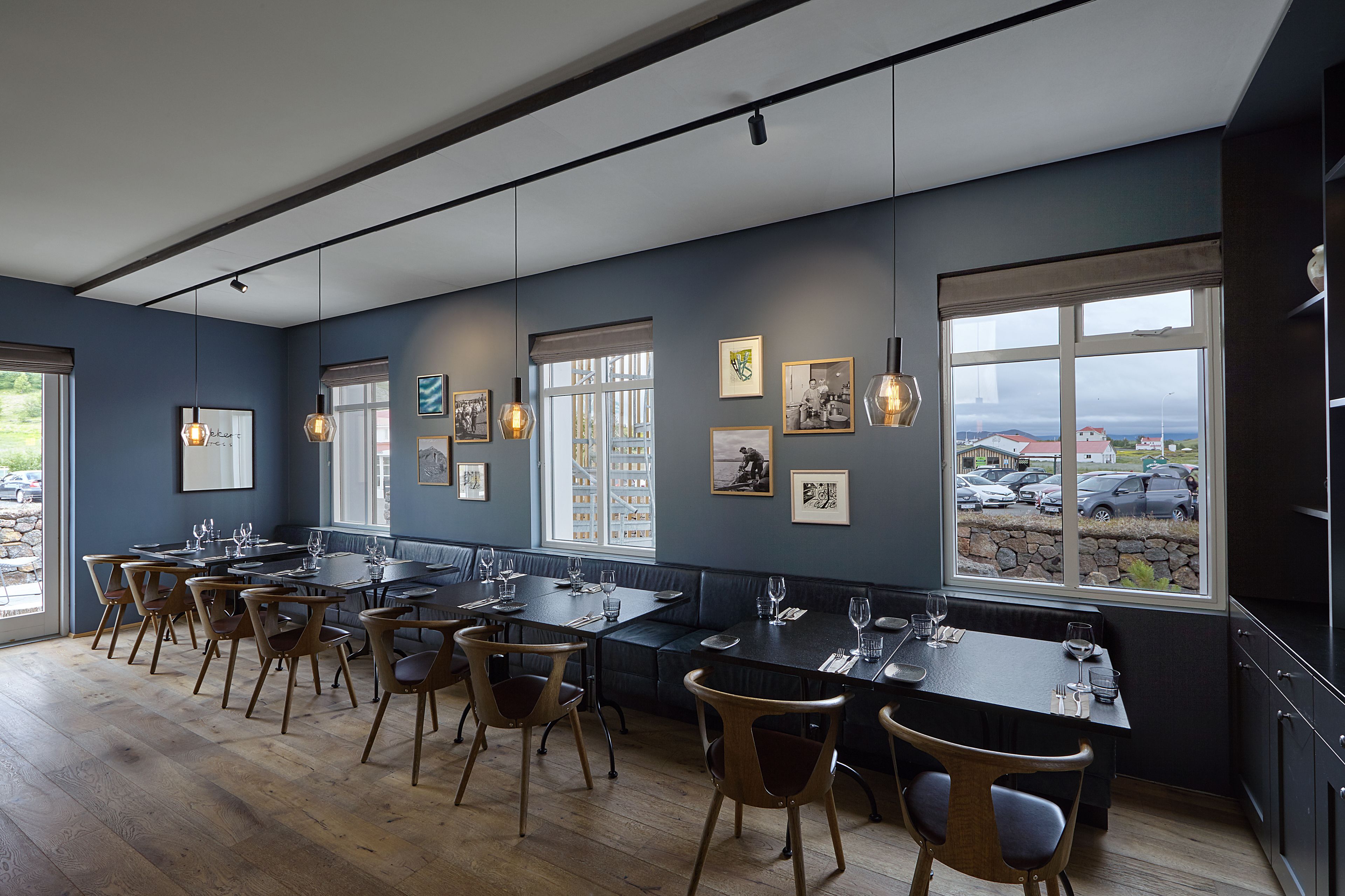 Een restaurant met meerdere eettafels en stoelen, grote ramen met uitzicht en wanddecoraties.