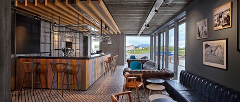 Un interior moderno con barra, asientos y ventanas amplias que ofrecen una vista.
