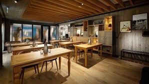 Une pièce spacieuse avec des tables et des chaises en bois, une grande fenêtre et un plafond en bois.
