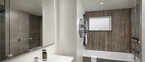 A modern bathroom with a large mirror, a white sink, a bathtub, and a toilet.