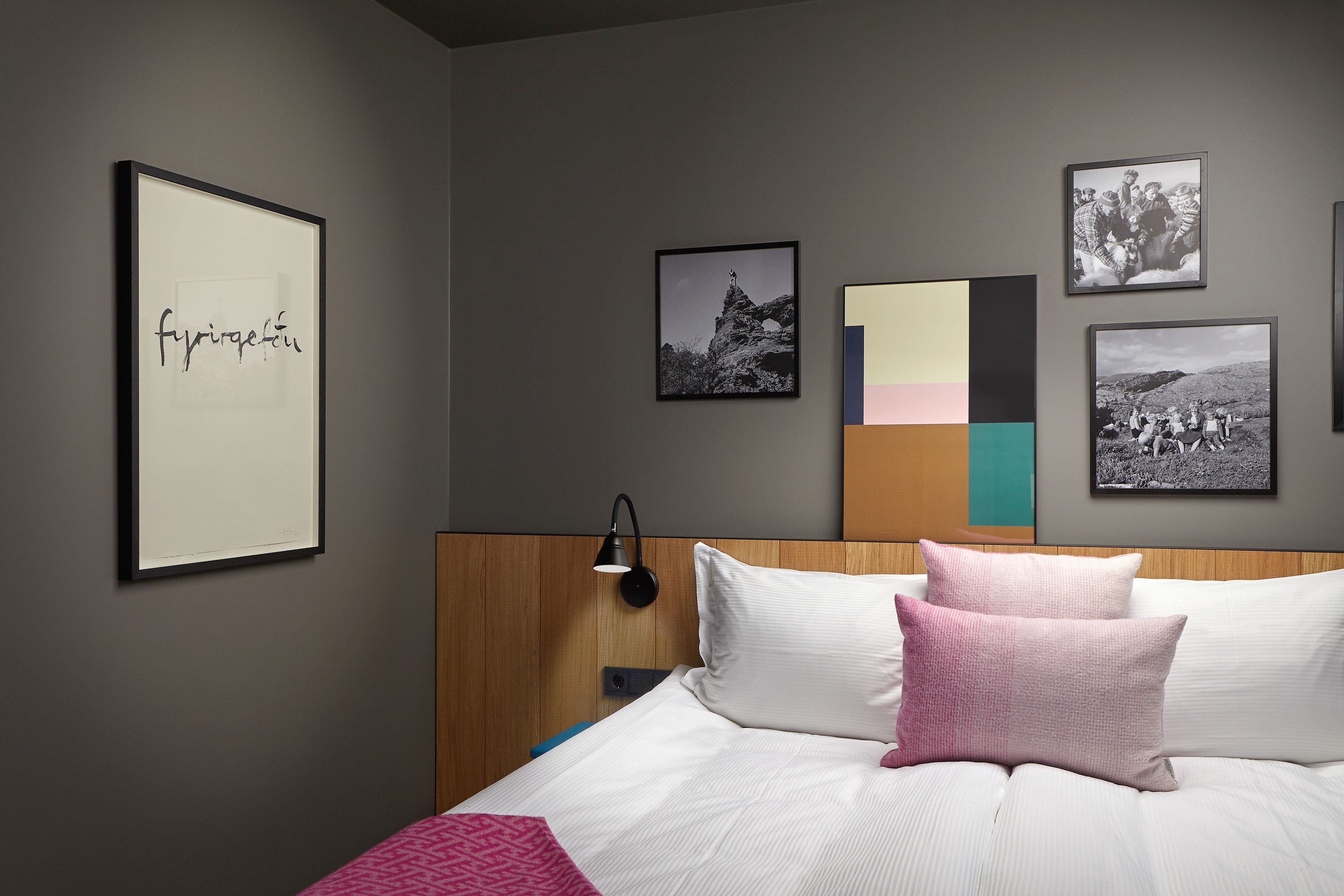 A neatly arranged bedroom with a bed, pillows, and framed pictures on the wall.