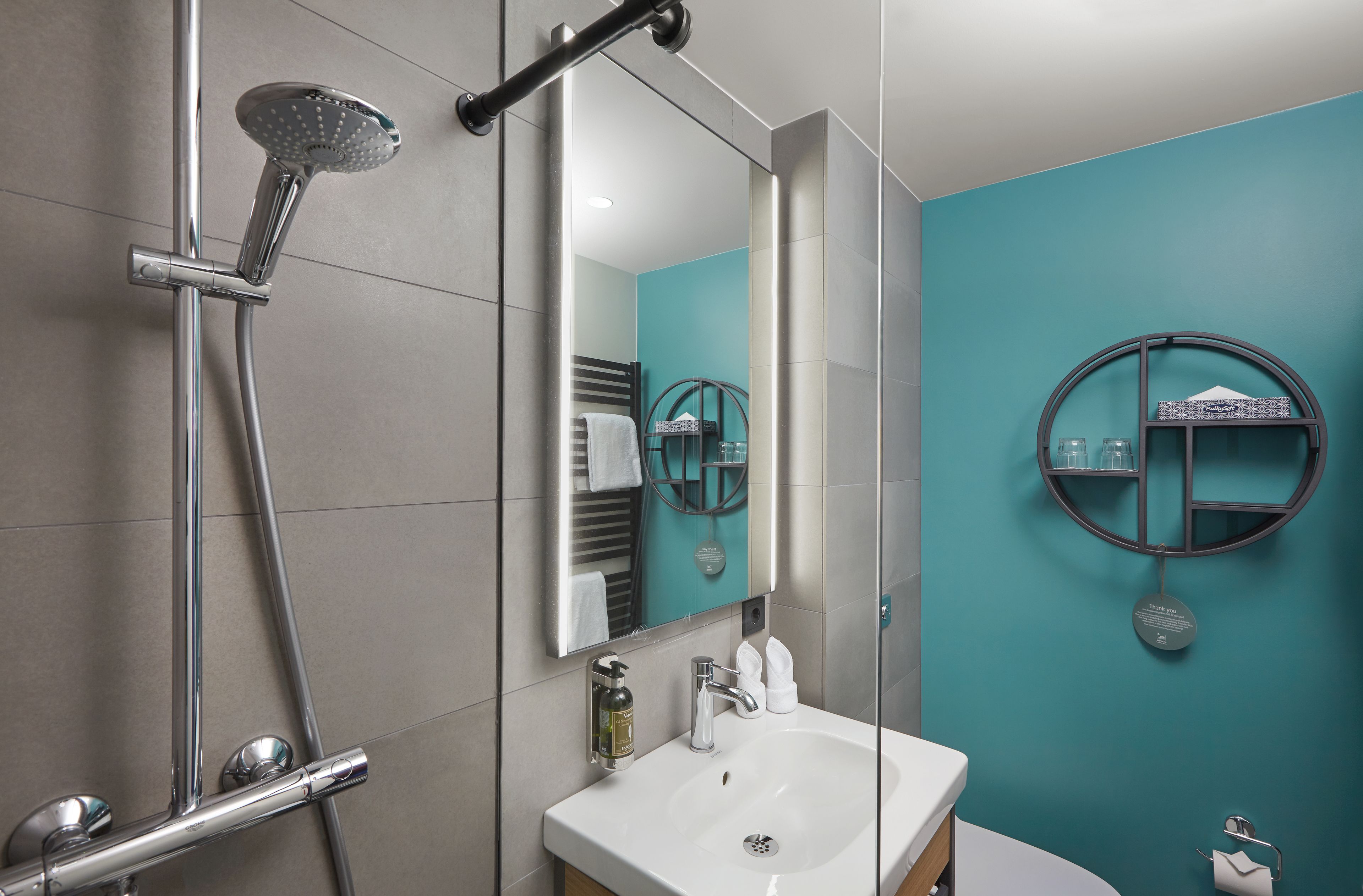 Un baño moderno con ducha, lavamanos y espejo.