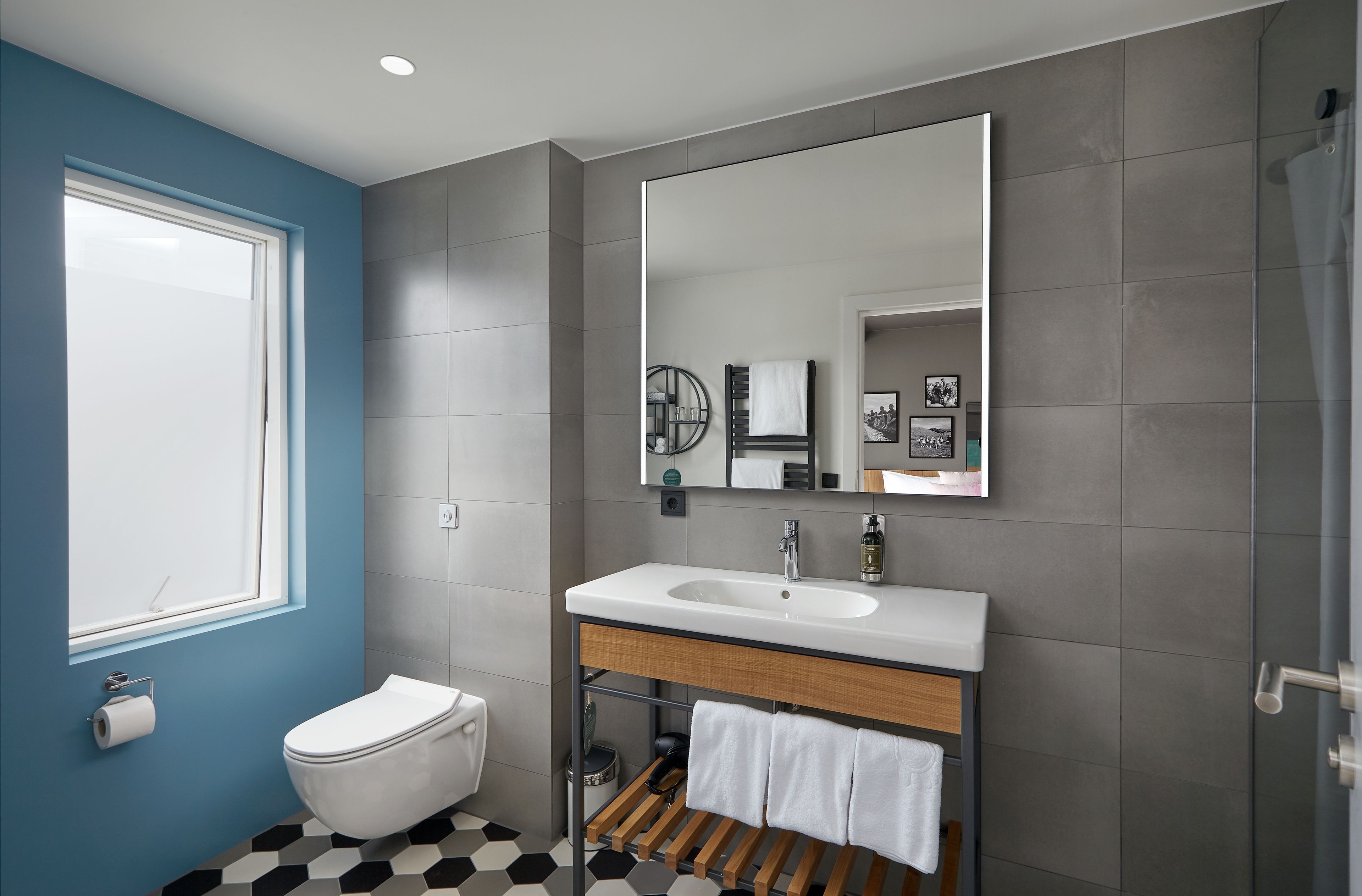 A modern bathroom with a white sink, a large mirror, and a toilet.