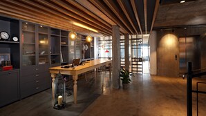 Un espace de bureau moderne avec une longue table en bois, des armoires grises et une grande fenêtre laissant entrer la lumière naturelle.