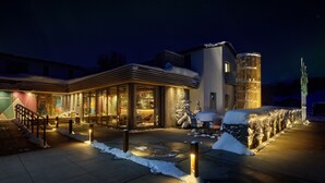 Un hôtel au design moderne, caractérisé par une façade en verre, une façade extérieure recouverte de neige et une entrée bien éclairée.