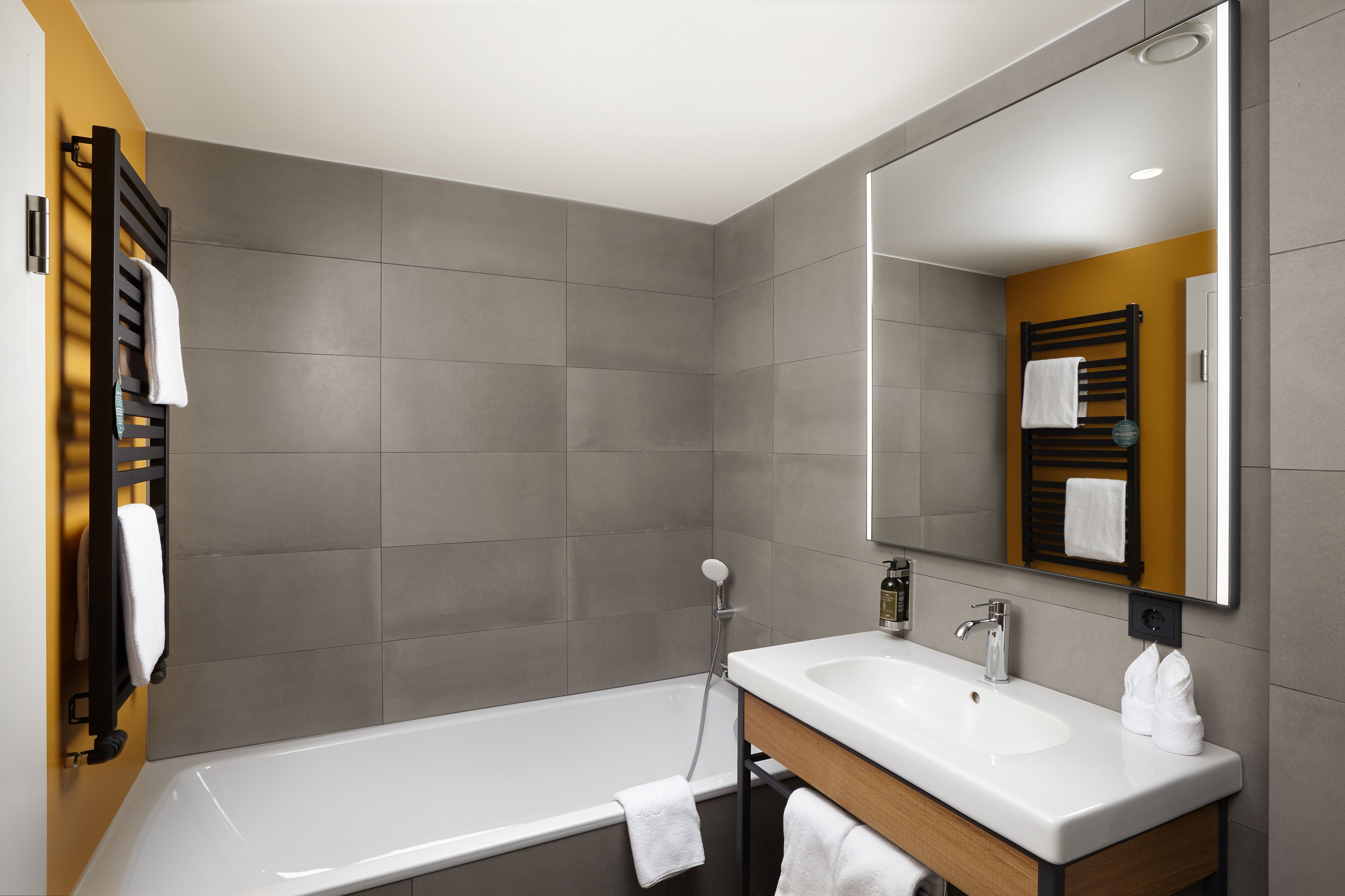 A modern bathroom with a bathtub, a sink, and a large mirror.