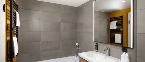 Un baño moderno con bañera, lavamanos y un espejo grande.