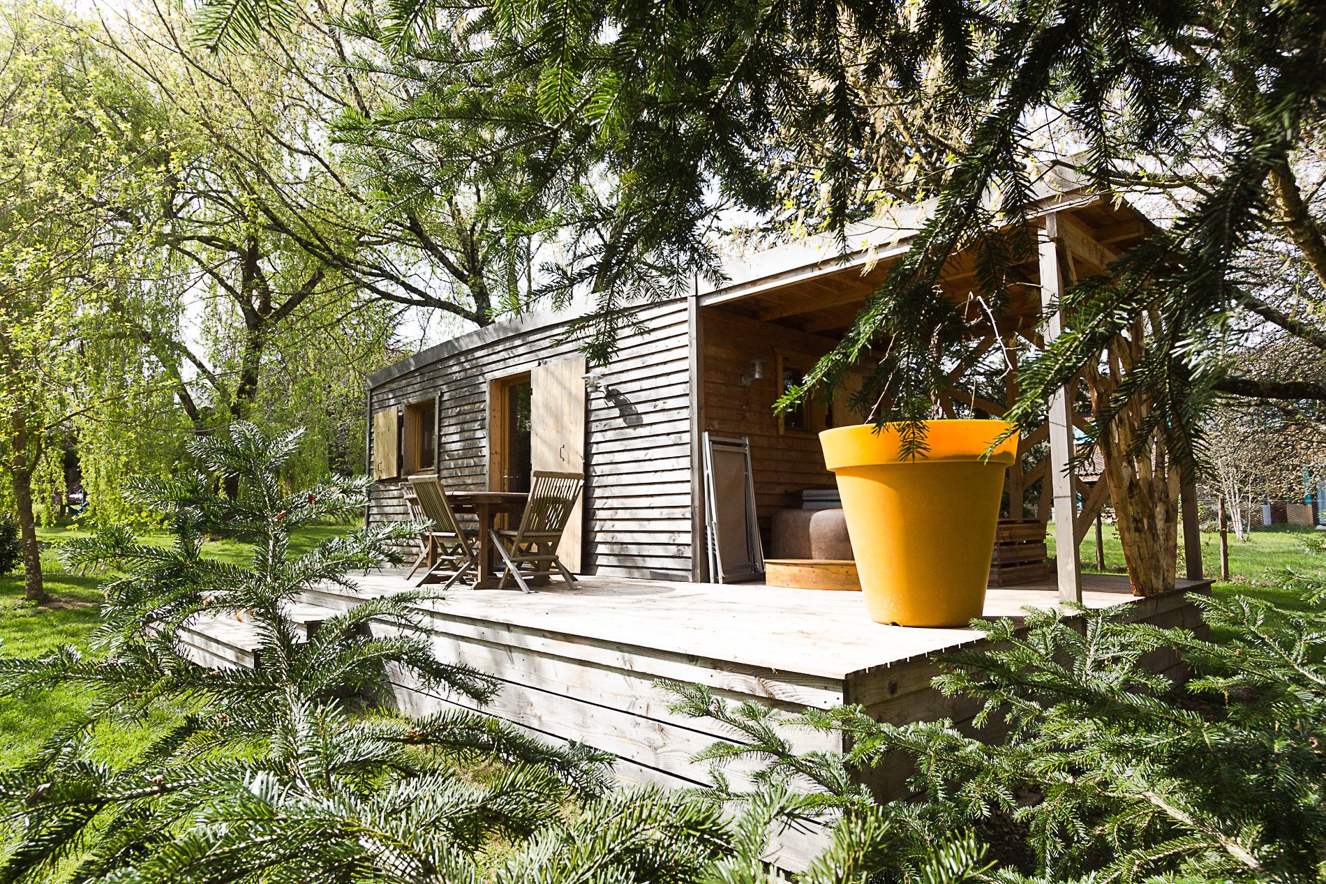 Una baita di legno con veranda, sedute all'aperto e un vaso da fiori di grandi dimensioni.