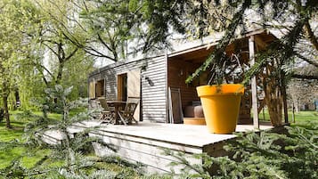Una baita di legno con veranda, sedute all'aperto e un vaso da fiori di grandi dimensioni.