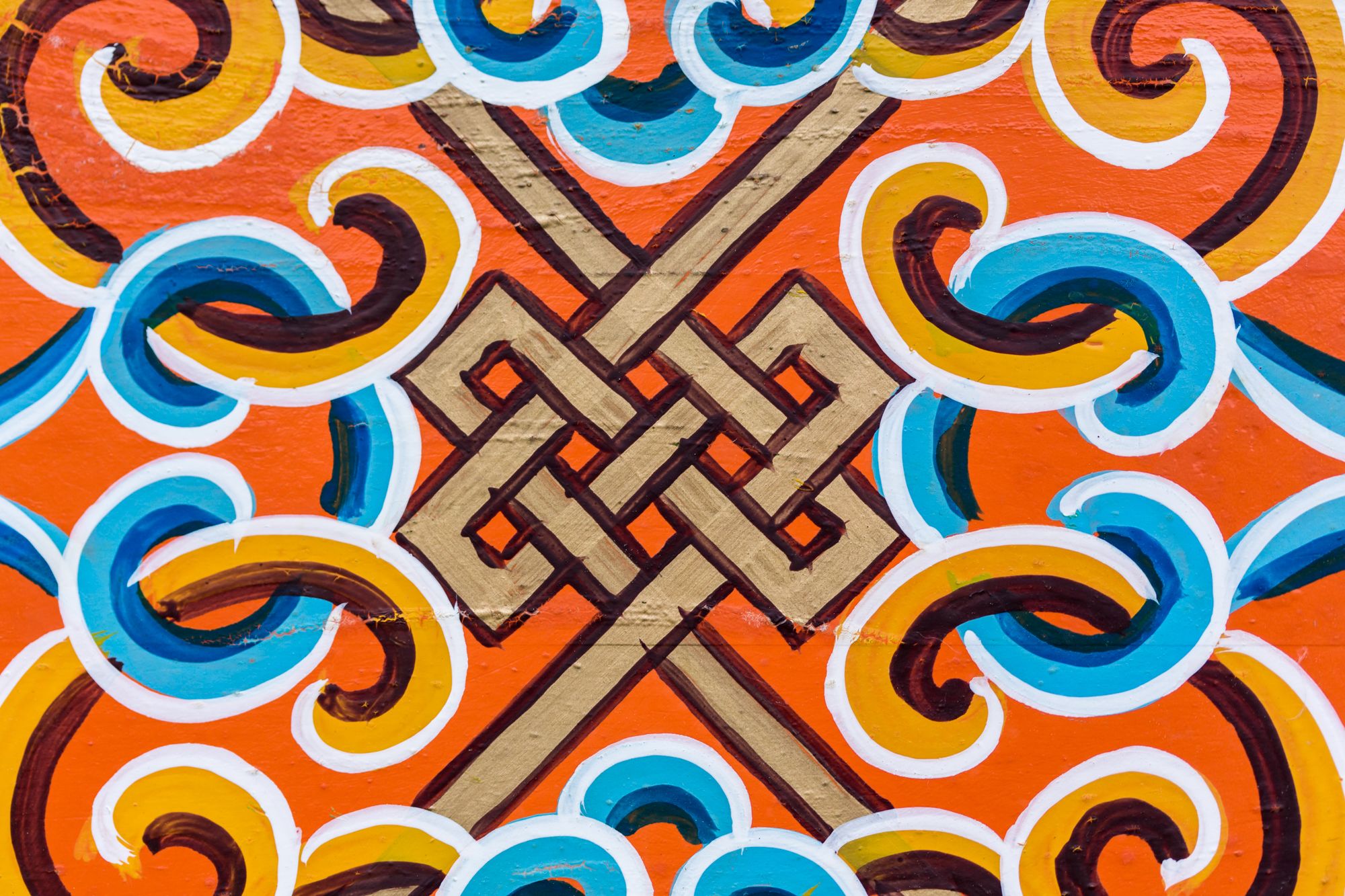 A vibrant geometric pattern with a central interlocking design, surrounded by swirling motifs.