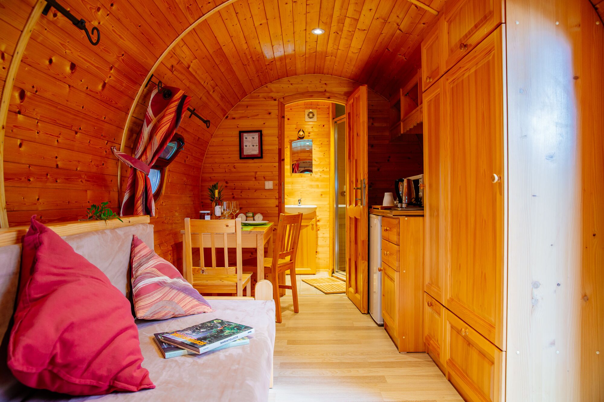 Un interior de cabaña acogedor con techo de madera, comedor y kitchenette.