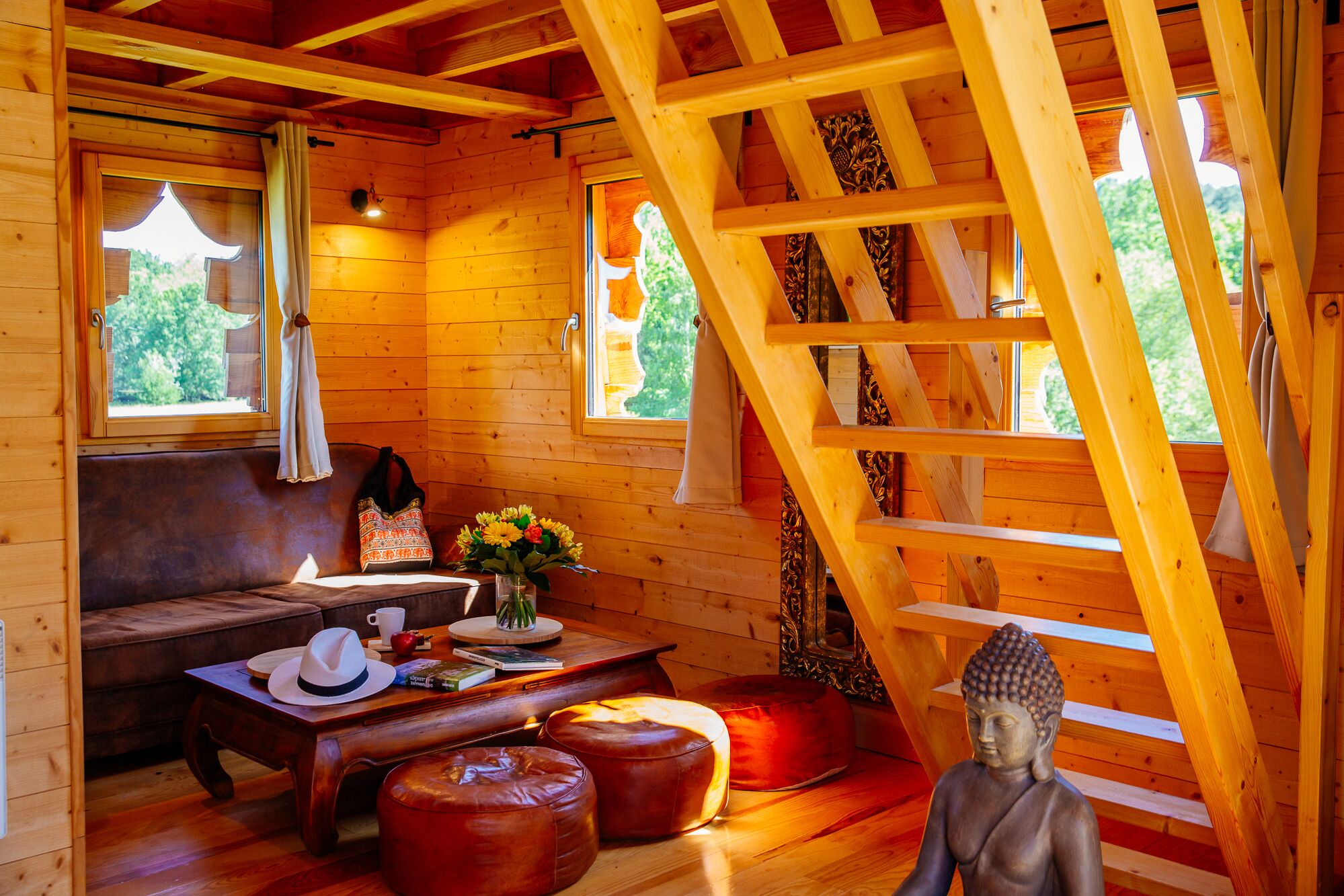 L’intérieur d’un chalet en bois chaleureux et accueillant, avec un canapé, une table basse et une statue de Bouddha.