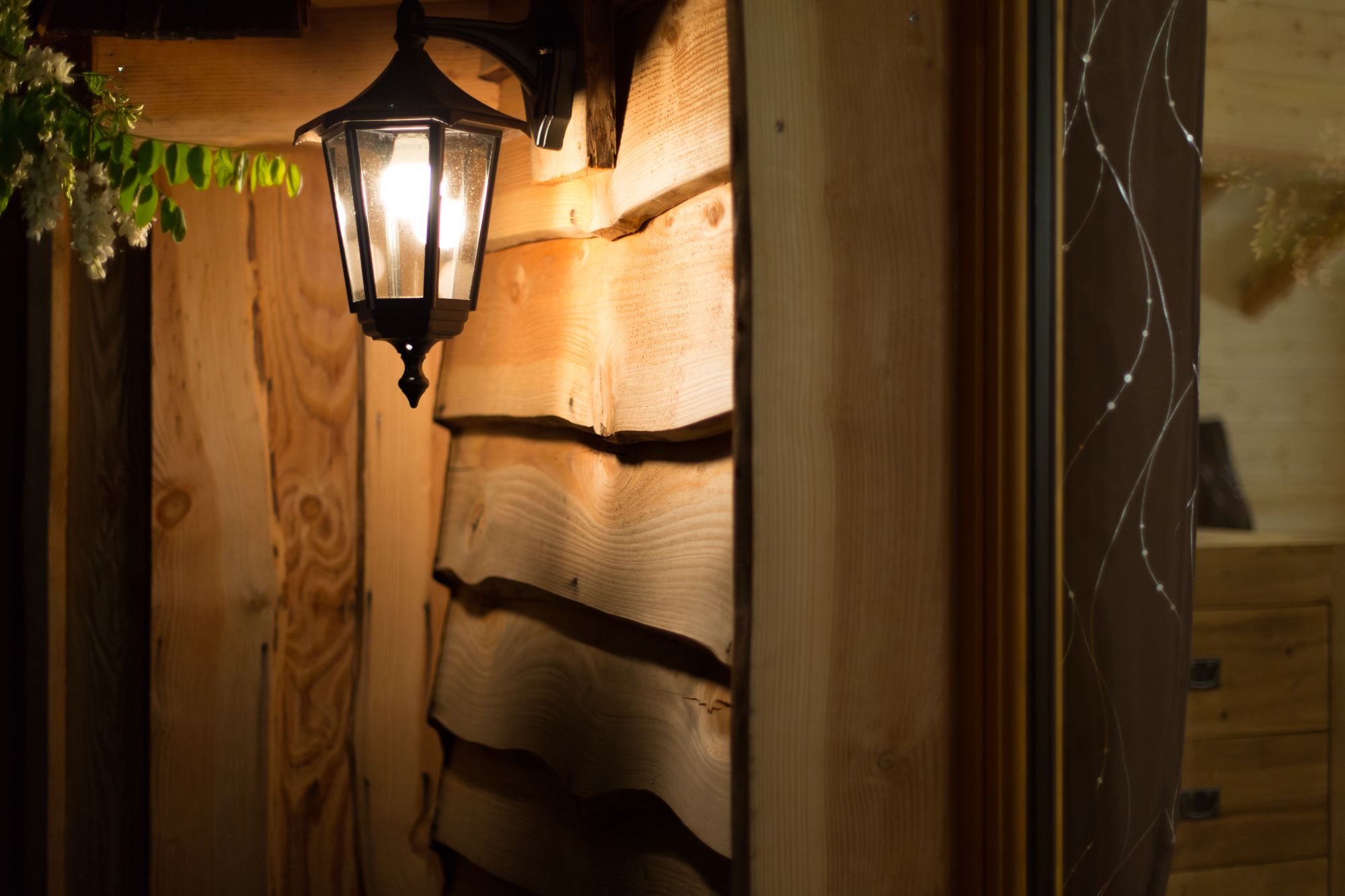 Een houten wand met een zwarte lantarenverlichting.