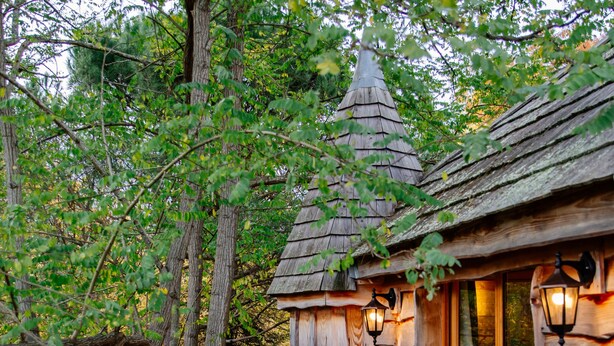A rustic wooden cabin with a dining area, a small tower-like structure, and lanterns. - Domaine Ecôtelia (Le Nizan)