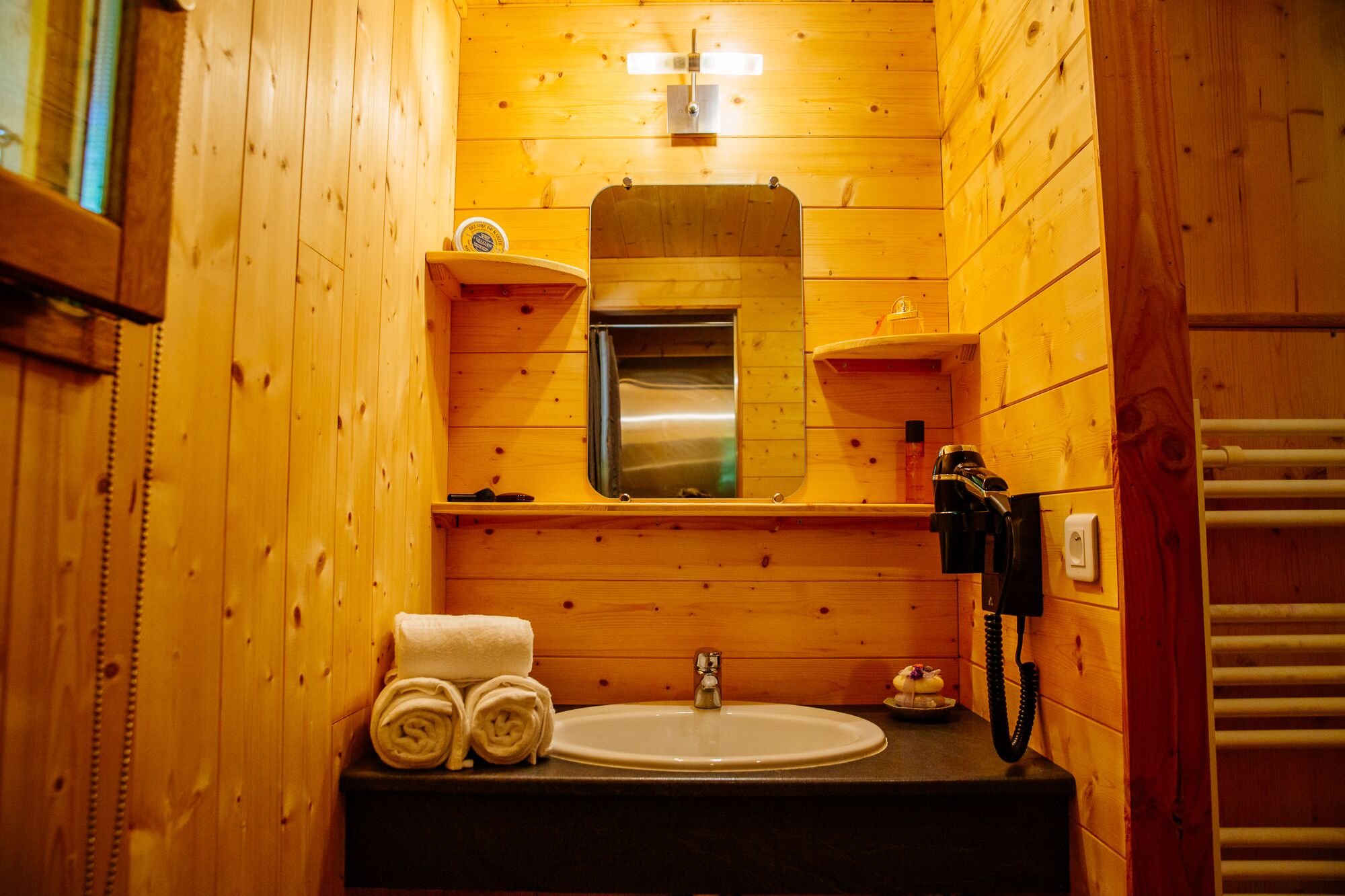 Ein Badezimmer im Holzblockhaus-Stil mit Waschbecken, Spiegel, Handtuchhalter und Telefon.