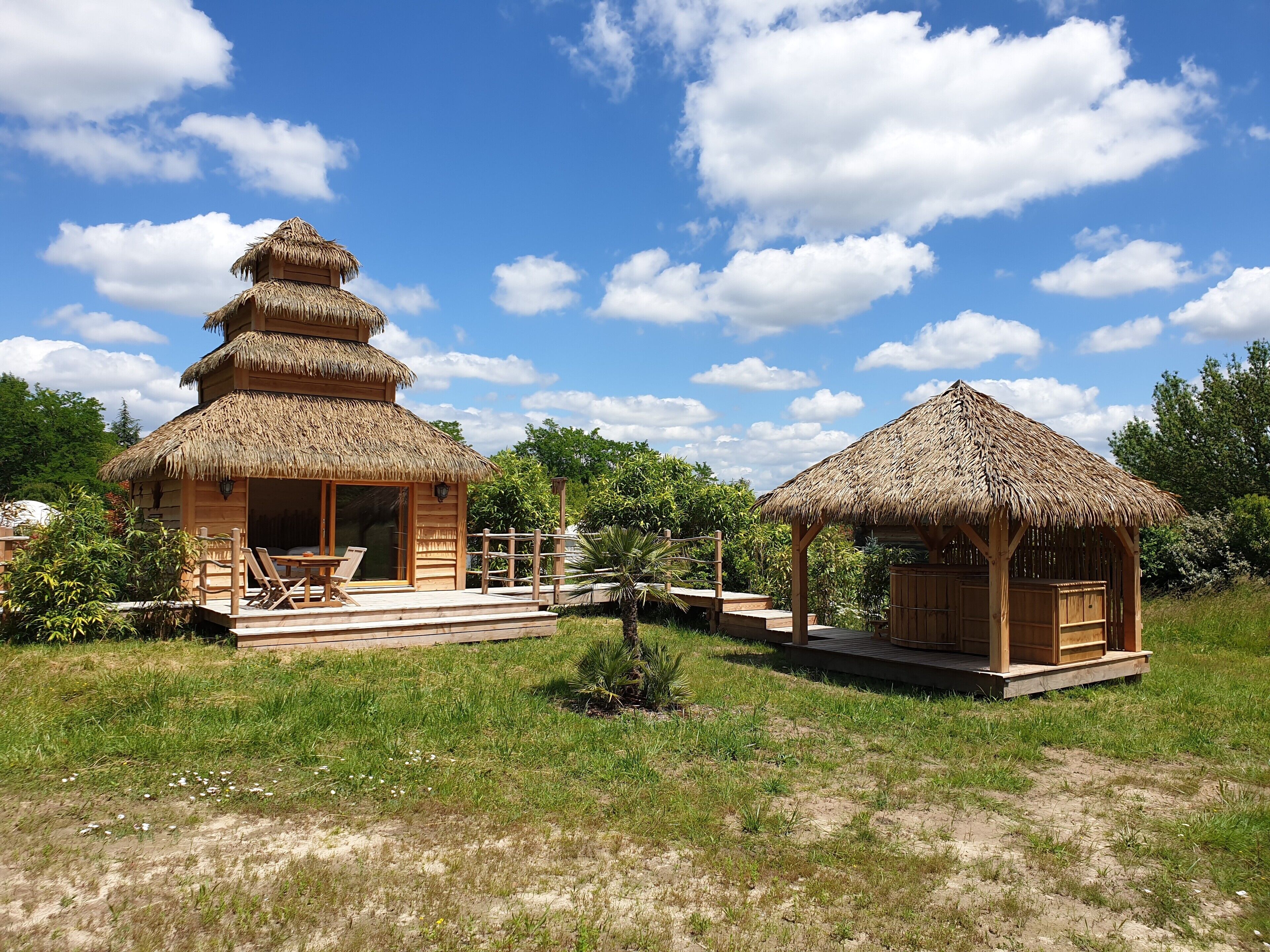A traditional wooden structure with a thatched roof, a wooden deck, and a small garden area.