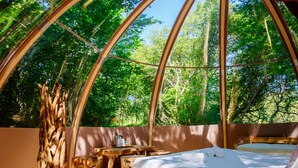 A tented accommodation with a bed, wooden stools, and a table with items on it. - Domaine Ecôtelia (Le Nizan)
