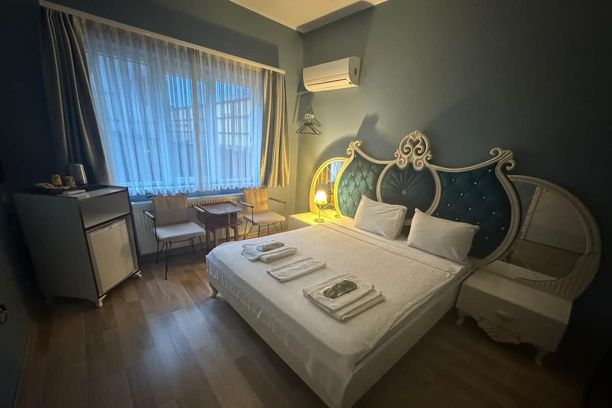 A bedroom with a bed, bedside tables, a desk, and a chair.