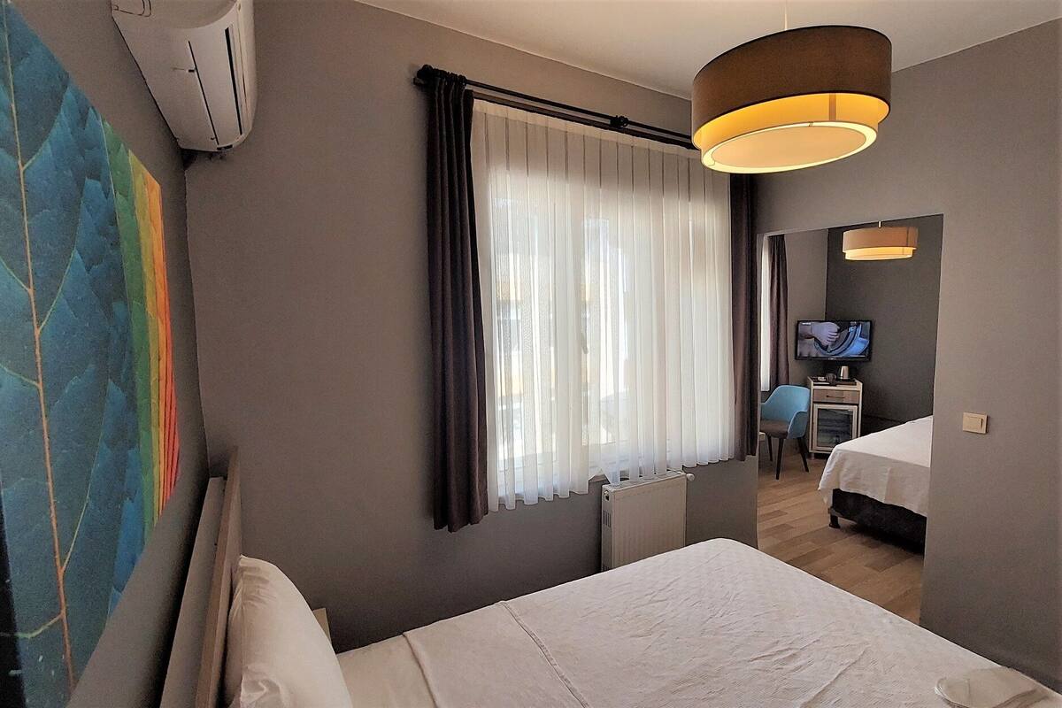 A hotel room with a bed, a television, a desk, and a window with curtains.