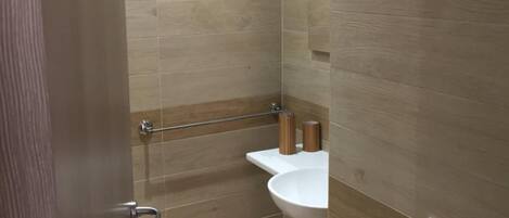 Een badkamer met een douche, wastafel en toilet.