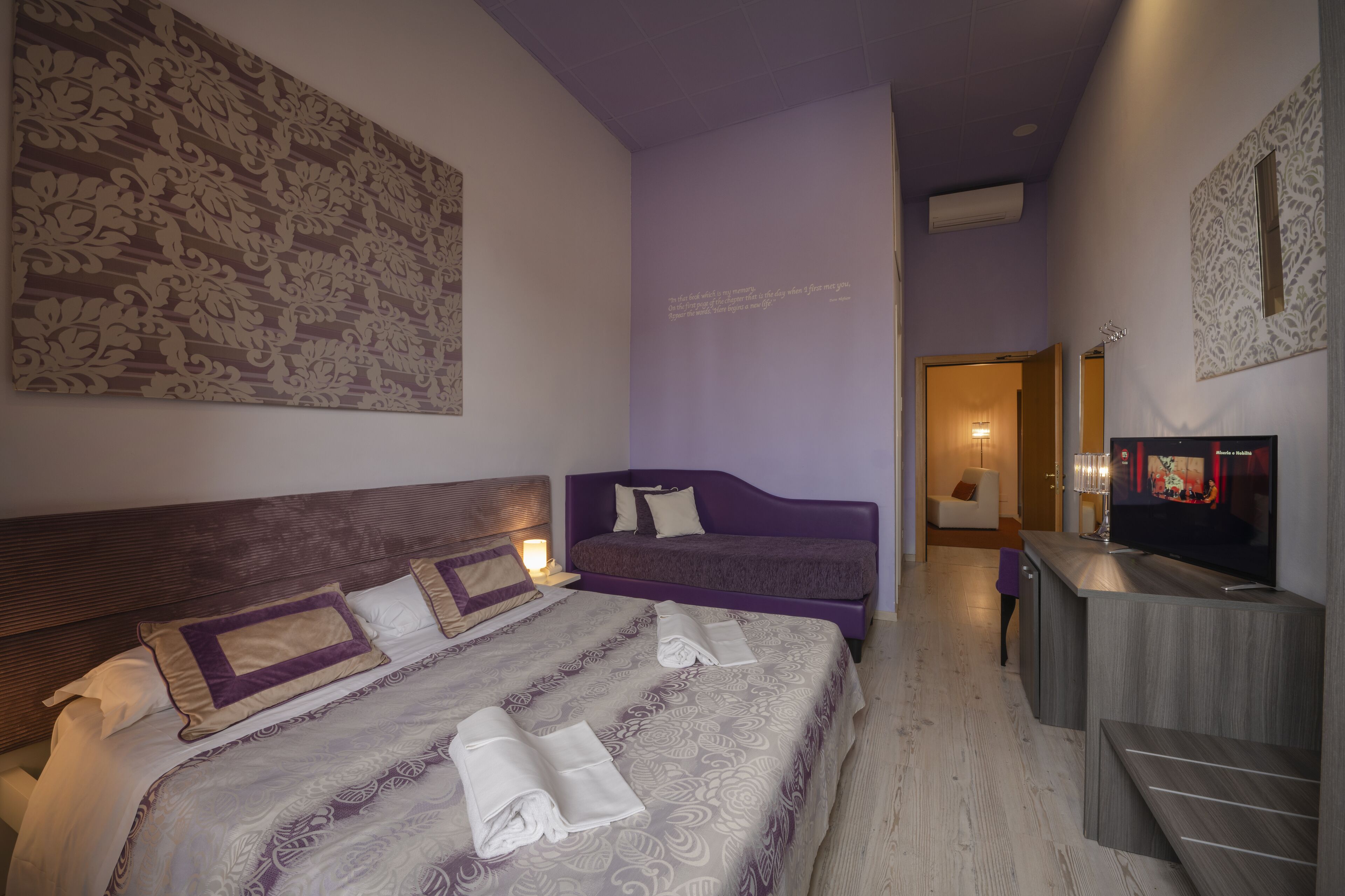 Una habitació d'hotel amb un llit gran, un sofà, una televisió i una taula de treball.