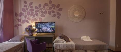 Habitación de hotel con dos camas, un escritorio con televisor, una silla y un adornado en la pared.