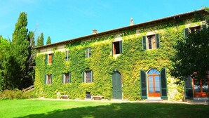 A building with a green ivy-covered exterior, multiple windows with shutters, and a well-maintained lawn. - Hotel Palazzo Renieri - 3stelle S (Colle di Val d'Elsa)