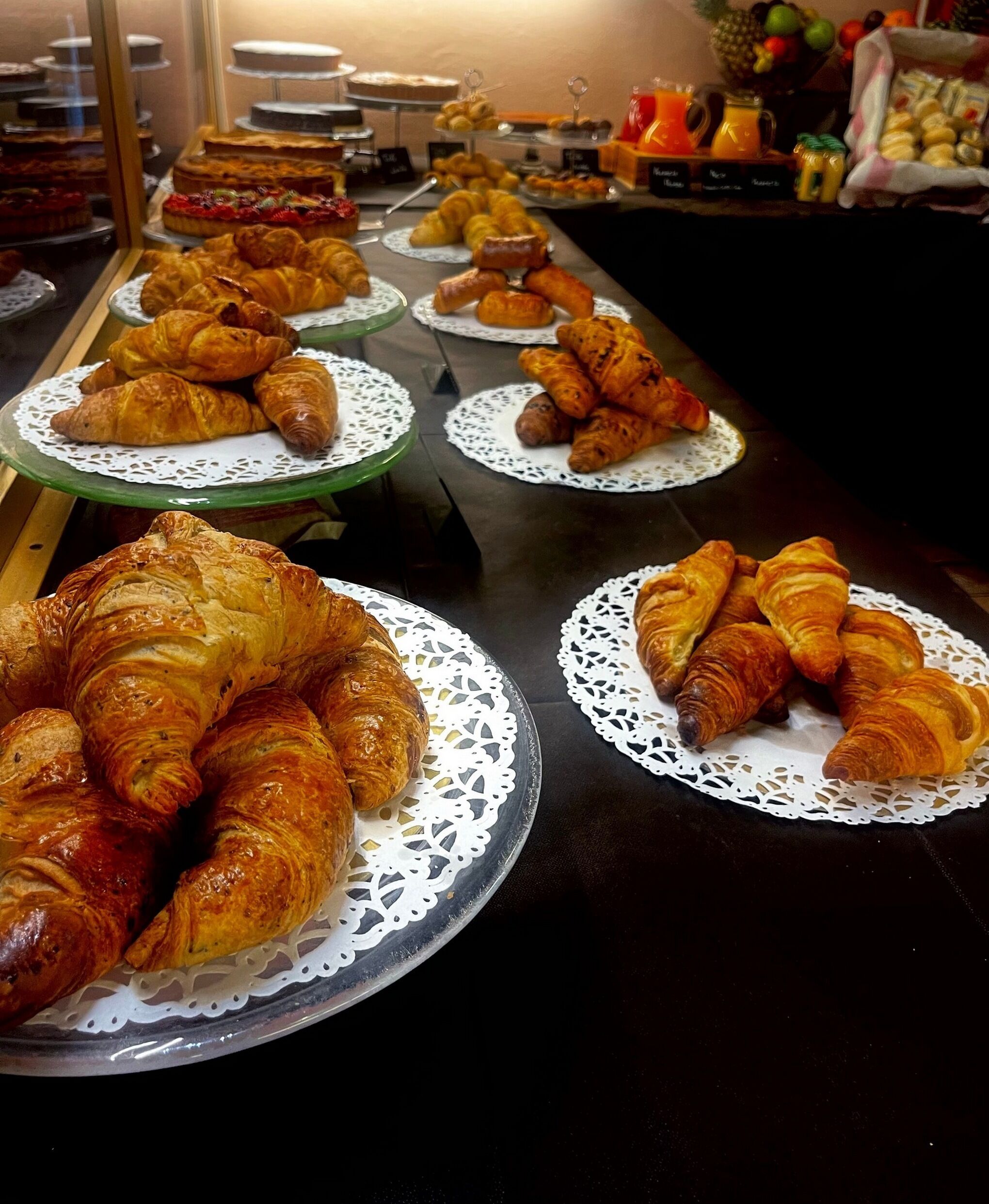 A buffet with various pastries and desserts displayed on plates and stands.