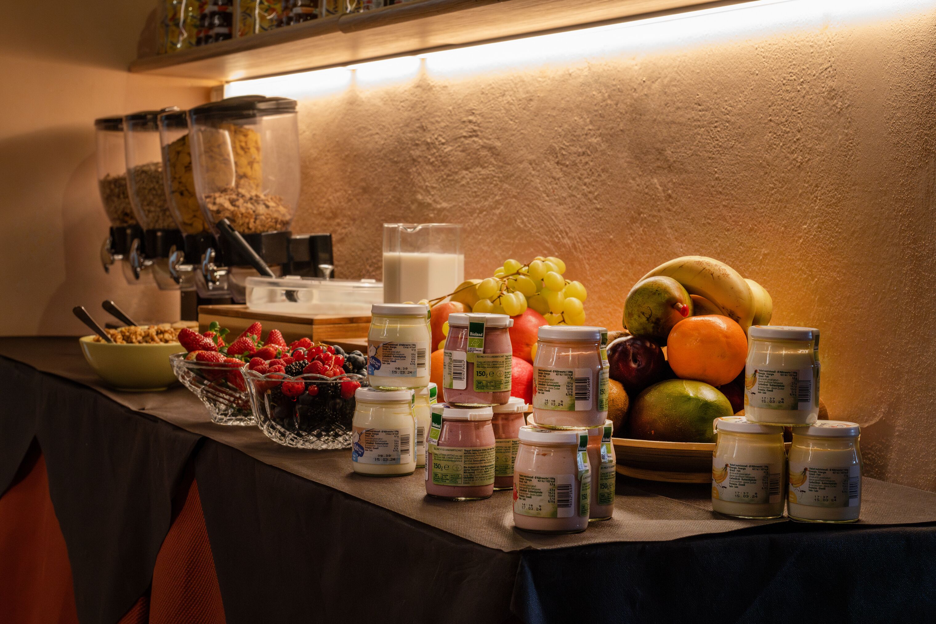 Una mesa de buffet con diversas opciones de comida, como frutas, yogur y granola.
