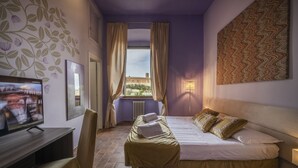 A hotel room with a bed, a TV, a desk, and a window with curtains. - Hotel Palazzo Renieri - 3stelle S (Colle di Val d'Elsa)