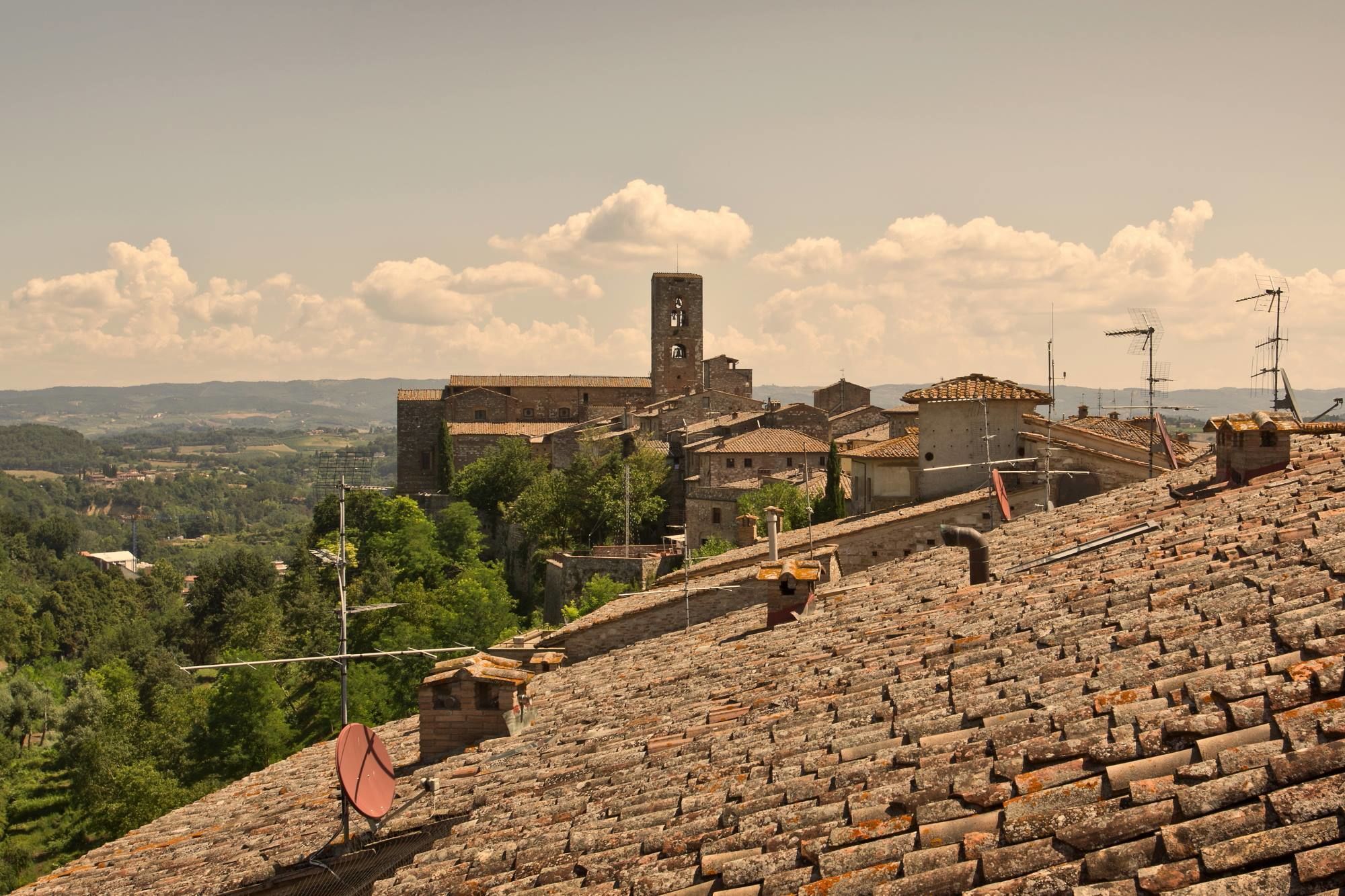 A historic town with stone buildings, a prominent tower, and terraced rooftops.