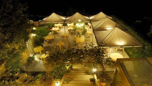 A tented outdoor dining area with tables and chairs, surrounded by potted plants and a staircase leading up. - Hotel Palazzo Renieri - 3stelle S (Colle di Val d'Elsa)