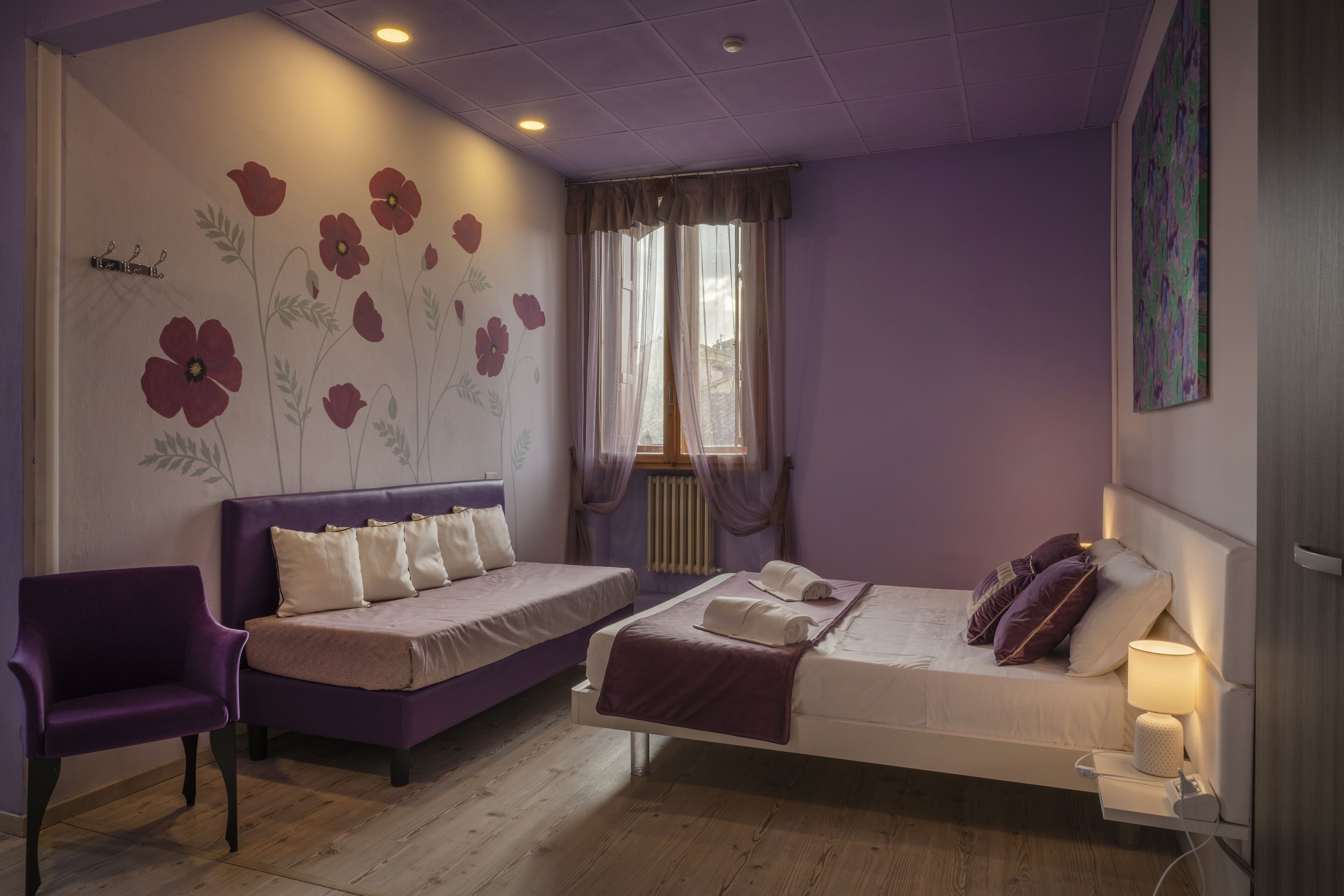 Een slaapkamer met twee bedden, een paarse stoel en een muurschildering.