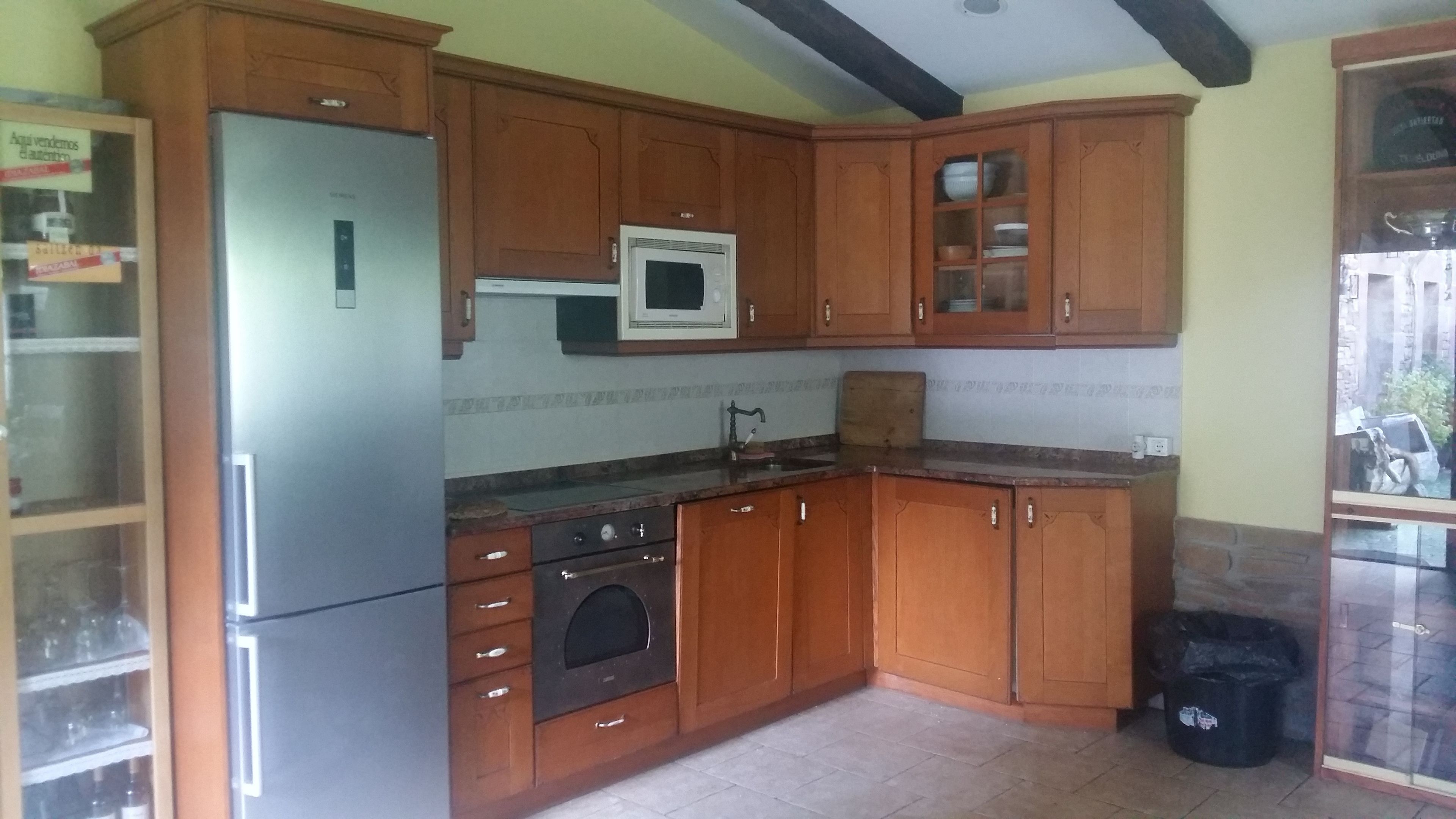 A kitchen with wooden cabinets, a refrigerator, an oven, and a microwave.